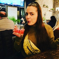 a woman sitting at a table with a drink in her hand